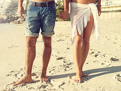 Buy stock photo Love, closeup and couple holding hands at a beach for walking, romance and bonding in nature together. Summer, zoom and legs or people at sea for travel, holiday or vacation with support or trust