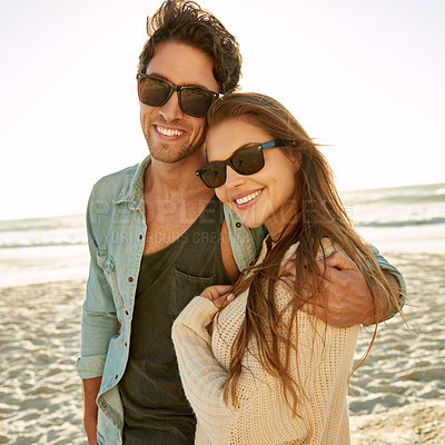 Buy stock photo Couple, sea and sunglasses with embrace, happy or care for fashion, eye protection or vacation in summer. Man, woman and hug with glasses at beach for sun, smile and love by ocean on tropical holiday