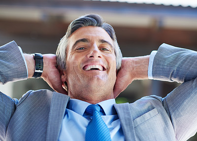 Buy stock photo Shot of a content businessman leaning back in his chair with his hands behind his head