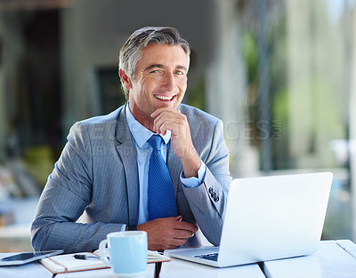 Buy stock photo Portrait of a confident-looking mature businessman working on a laptop