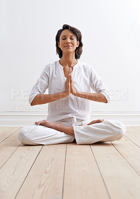 Buy stock photo Shot of a beautiful young woman sitting in the lotus position during a yoga session