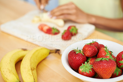Buy stock photo Woman, hands and cutting fruit in kitchen for diet, healthy meal or preparing salad or smoothie at home. Closeup of female person or vegetarian slicing banana and strawberry for natural nutrition