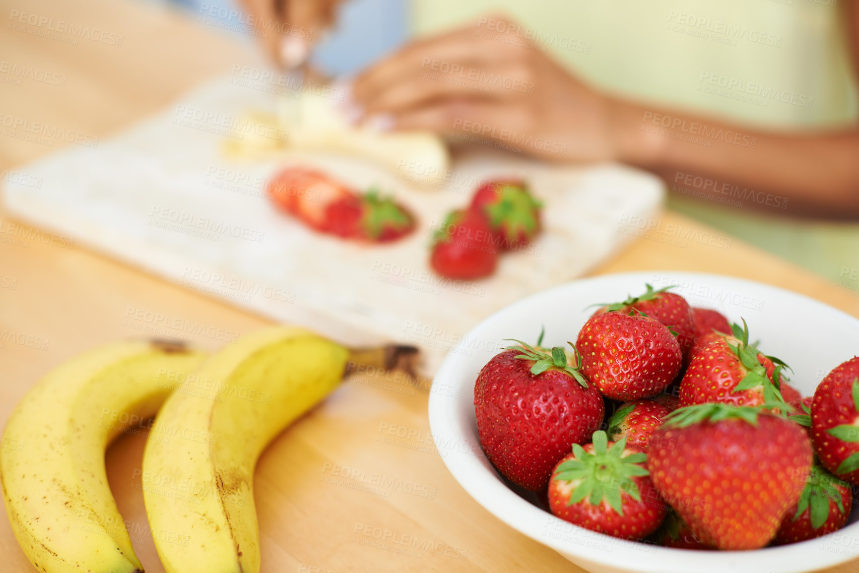 Buy stock photo Woman, hands and cutting fruit in kitchen for diet, healthy meal or preparing salad or smoothie at home. Closeup of female person or vegetarian slicing banana and strawberry for natural nutrition