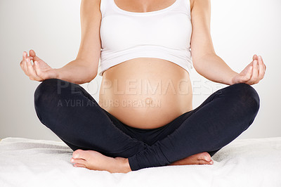 Buy stock photo Cropped shot of a pregnant woman meditating in the lotus position