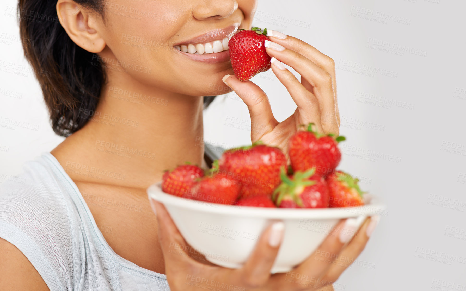 Buy stock photo Health, strawberries and closeup of woman in a studio for wellness, nutrition and organic diet. Smile, vitamins and zoom of female person eating a fruit for healthy vegan snack by gray background.