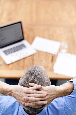 Buy stock photo Rearview shot of a businessman reclining in his chair while working with a laptop