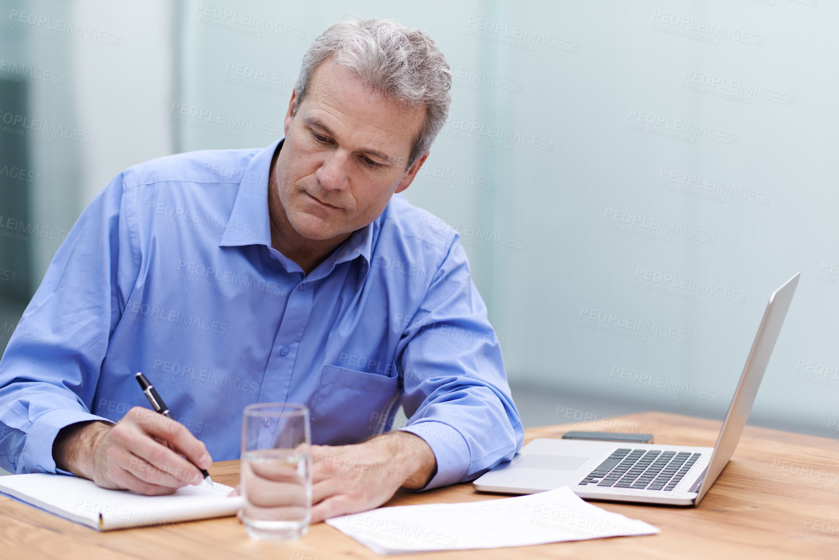 Buy stock photo Shot of a mature businessman writing notes at his desk in the office