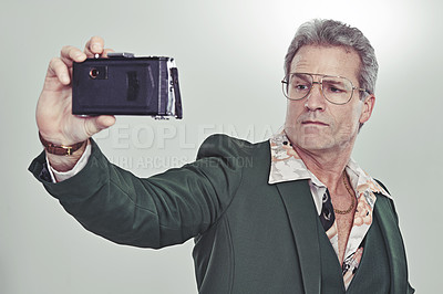 Buy stock photo Mature man, fashion and selfie with camera in photography, memory or cool style on a gray studio background. Senior, male person with glasses and posing for photo, picture or trend in formal clothing