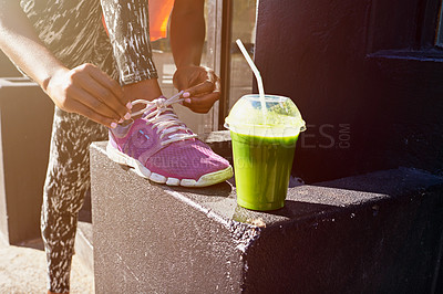 Buy stock photo Woman, hands and tying shoe with smoothie for fitness, diet or health and wellness in city. Closeup, female person or runner with drink or tie laces for workout preparation or exercise in urban town