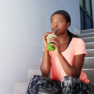 Buy stock photo Shot of an attractive young woman drinking juice while exercising outdoors