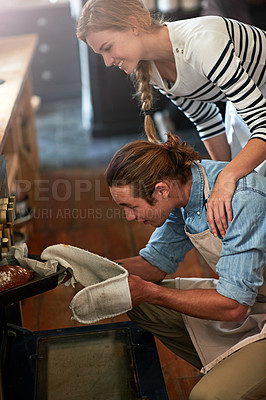 Buy stock photo Shot of a young couple checking up on their bread in the oven