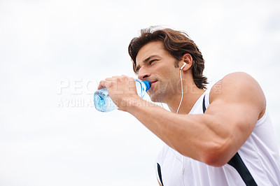 Buy stock photo Man, drinking water on break from workout, thirsty and listening to music, podcast or song on run. Male athlete, earphones and hydrated for exercise, cardio and fitness on white background in mockup