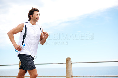 Buy stock photo Cropped shot of a handsome young man running along the promenade