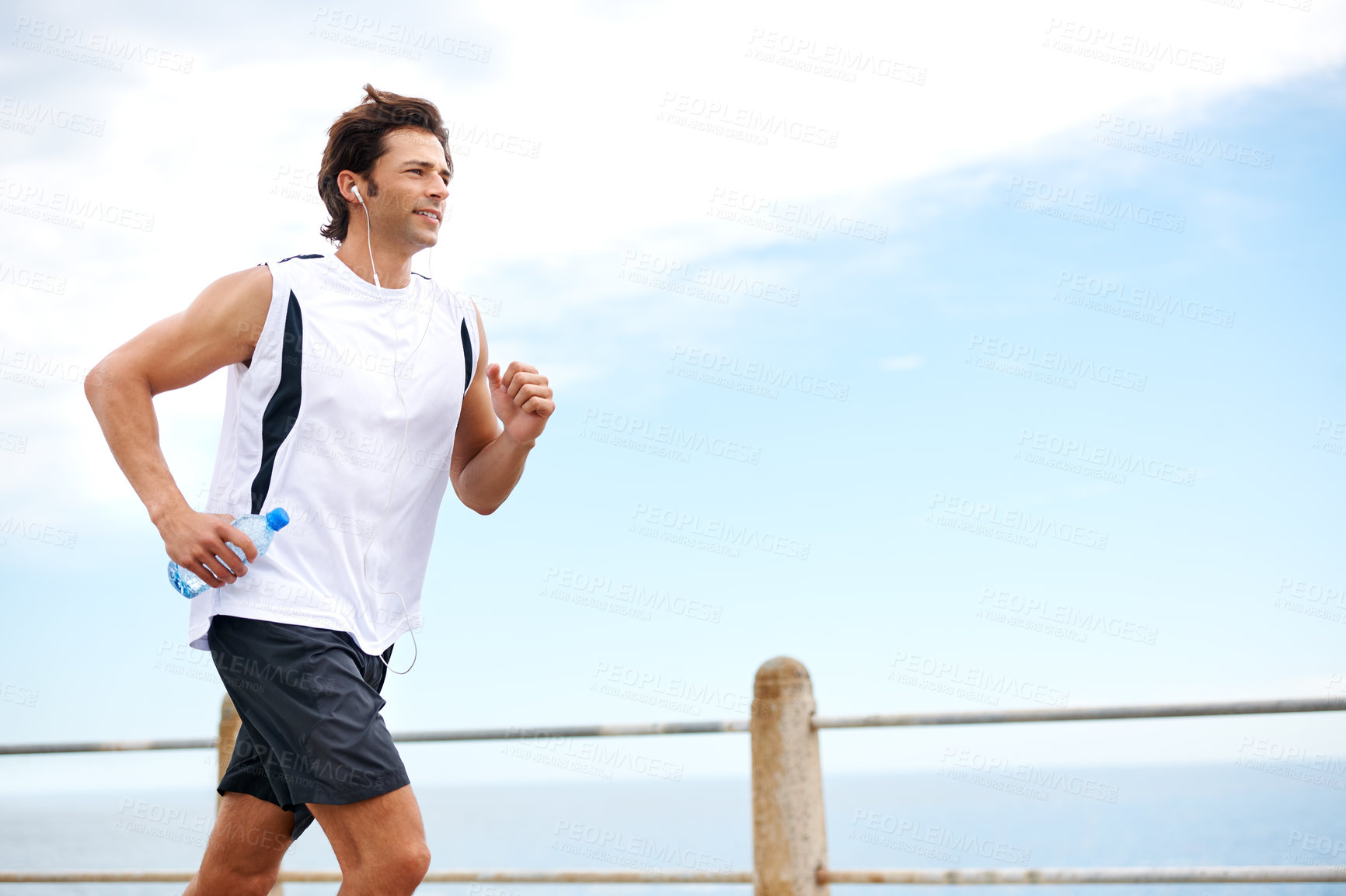 Buy stock photo Cropped shot of a handsome young man running along the promenade
