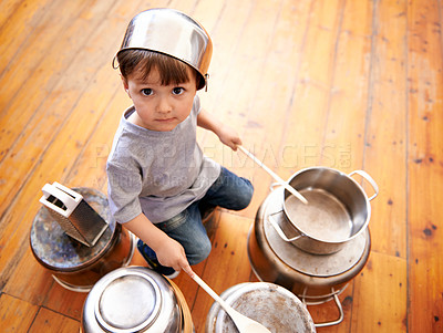 Buy stock photo Portrait, boy child playing drums on pots on a floor, curious and enjoying music. Face, top view and kid with pans for musical entertainment, silly and carefree in kitchen in his home on the weekend