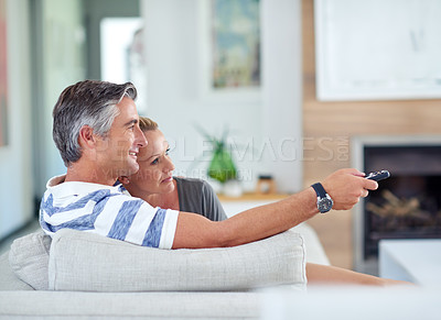 Buy stock photo Shot of mature couple cuddling on the sofa while watching movies at home