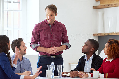Buy stock photo Cropped shot of a handsome businessman listening to his colleagues during a business meeting