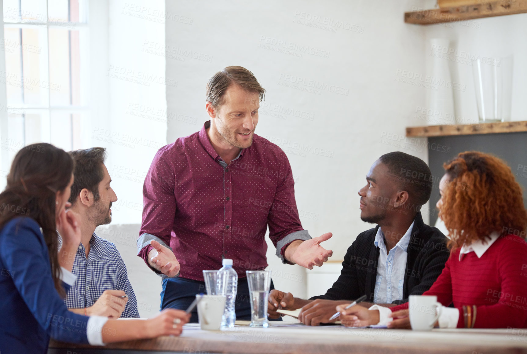 Buy stock photo Cropped shot of a handsome businessman addressing his colleagues during a business meeting