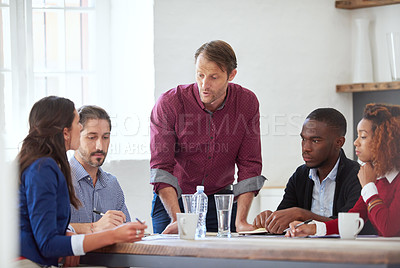 Buy stock photo Cropped shot of a handsome businessman listening to his colleagues during a business meeting