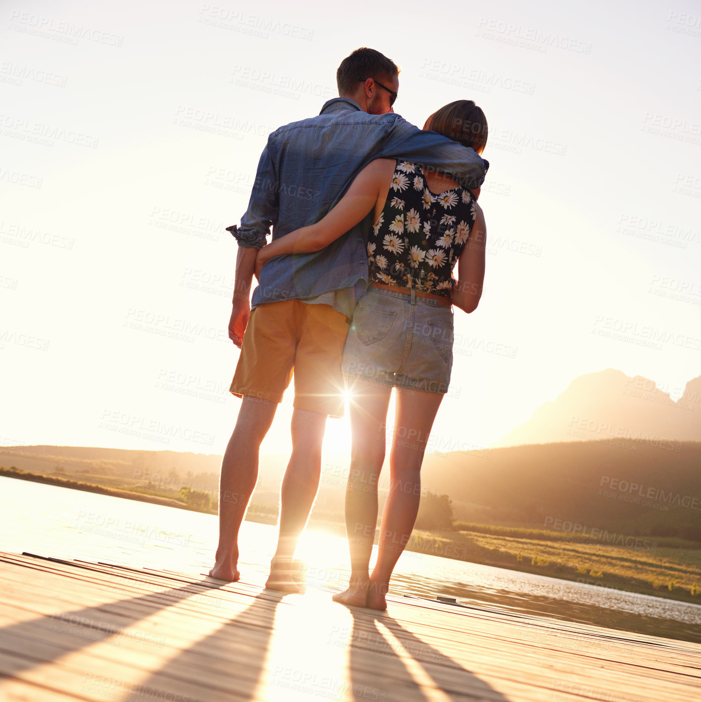 Buy stock photo Couple, hug and sunset on dock by lake for memory, vacation and love in countryside. People, man and woman with back, water and mountain view in nature with bonding, relationship and holiday in Italy