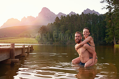 Buy stock photo Shot of an affectionate young couple enjoying a swim together at a lake