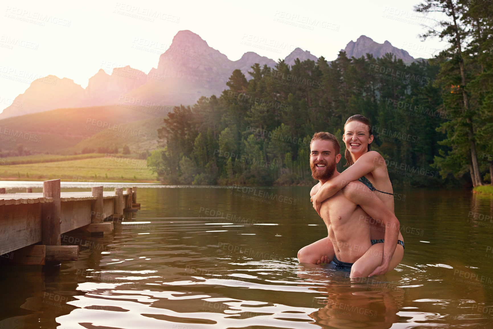 Buy stock photo Shot of an affectionate young couple enjoying a swim together at a lake
