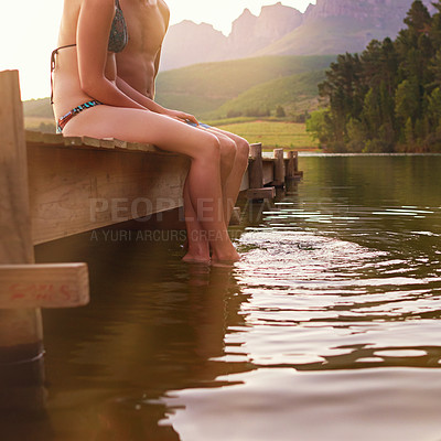Buy stock photo Shot of a young couple sitting on a dock at a lake