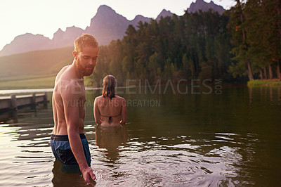 Buy stock photo Shot of an affectionate young couple enjoying a swim at a lake
