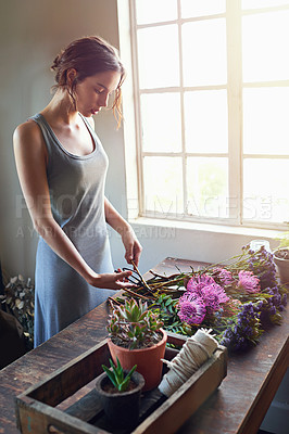Buy stock photo Shot of a young florist cutting flowers to make up a bouquet counter top