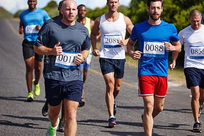 Buy stock photo Shot of a group of young men running a marathon
