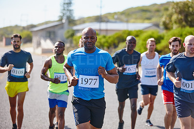 Buy stock photo Shot of a group of young men running a marathon