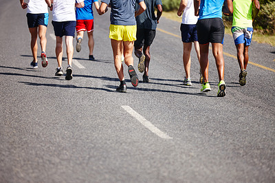 Buy stock photo Cropped rearview shot of a group of men running a road race