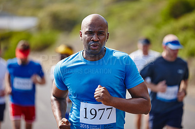 Buy stock photo Shot of a young man running a marathon with other runners in the background
