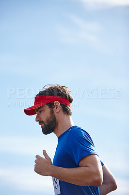 Buy stock photo Shot of a young man running a marathon with the sky as background