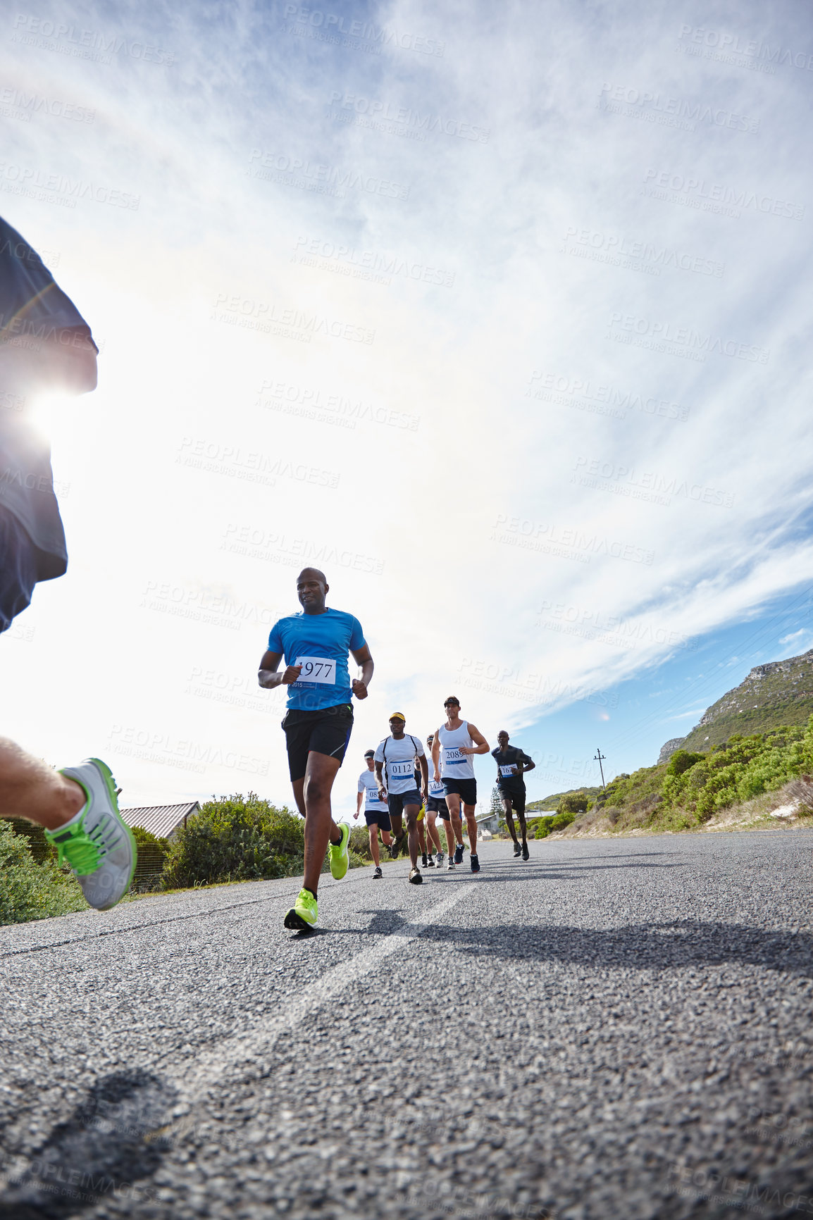 Buy stock photo Shot of a group of young men running a marathon