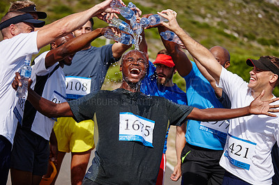 Buy stock photo Shot of a group of young men pouring water over their friend after running  a marathon