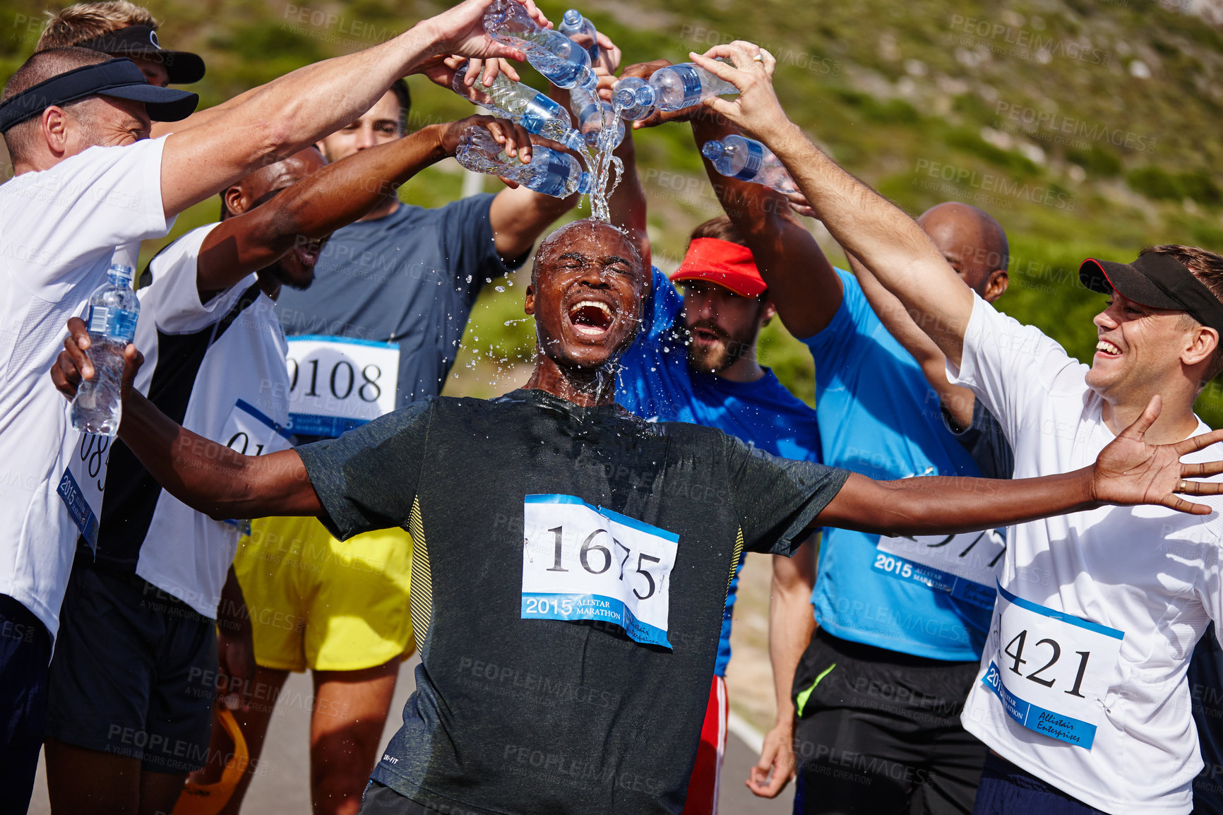Buy stock photo Shot of a group of young men pouring water over their friend after running  a marathon