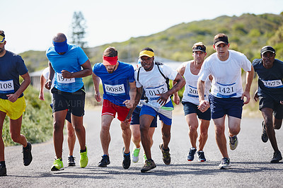 Buy stock photo Shot of a group of young male runners starting out a marathon