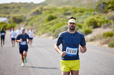 Buy stock photo Shot of a young man running ahead of the pack in a marathon