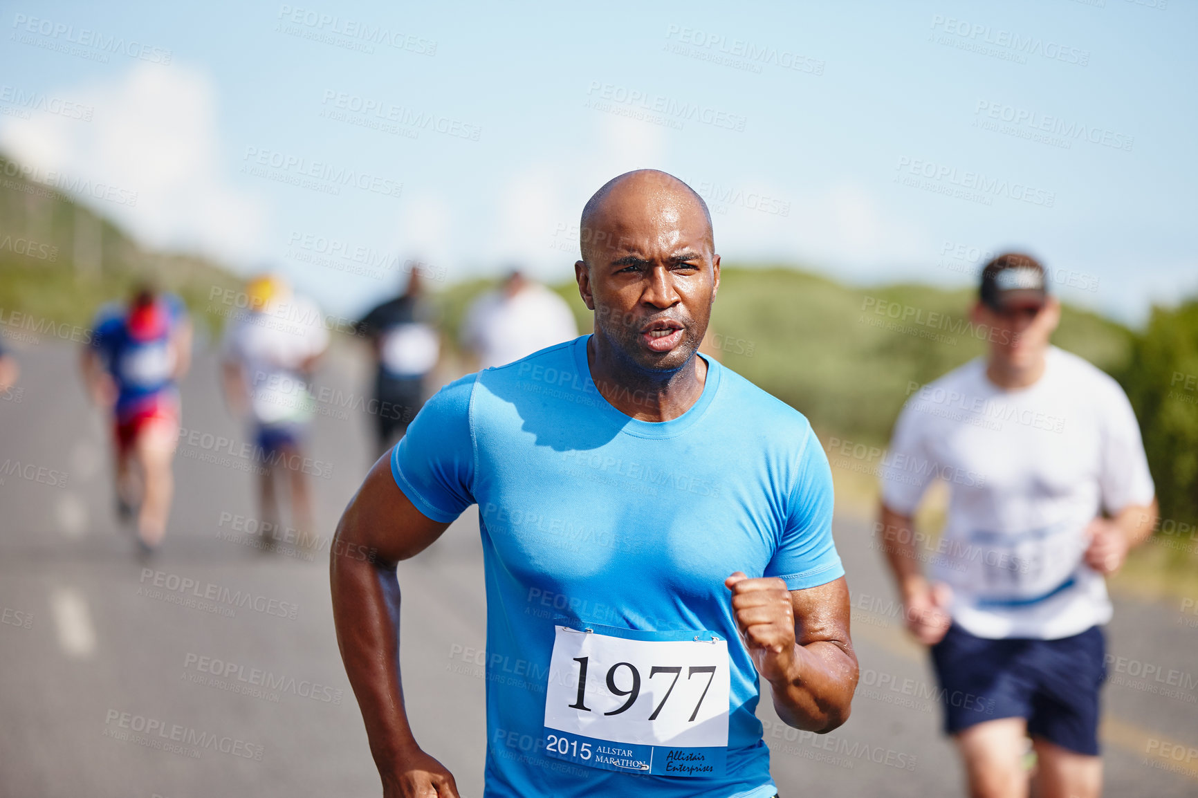 Buy stock photo Shot of a young man running ahead of the pack in a marathon