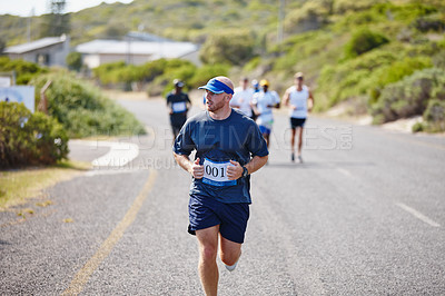 Buy stock photo Shot of a young man running ahead of the pack in a marathon