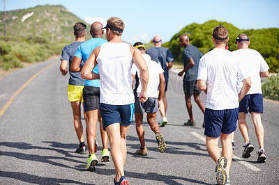 Buy stock photo Rearview shot of a group of young men running a marathon