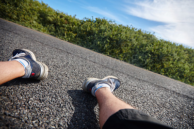 Buy stock photo Shot of an exhausted runner's legs as he sits next to the road