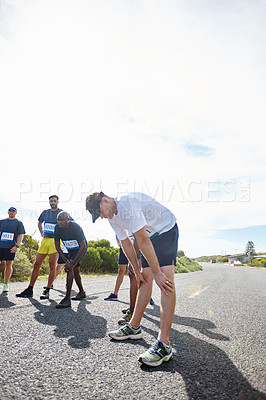 Buy stock photo Shot of a group of male runners getting focused before a road race