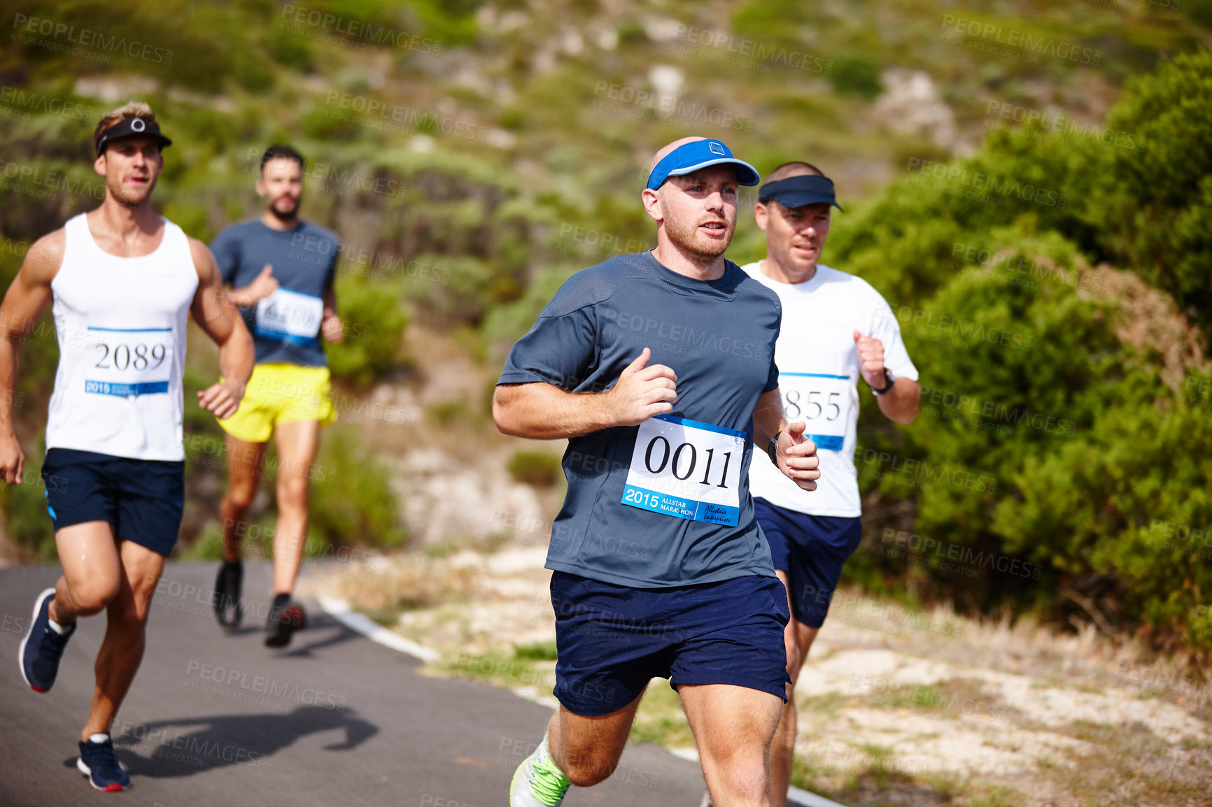 Buy stock photo Shot of a group of young men running a marathon