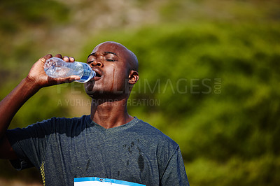 Buy stock photo Shot of a young male runner drinking from his water bottle during a race