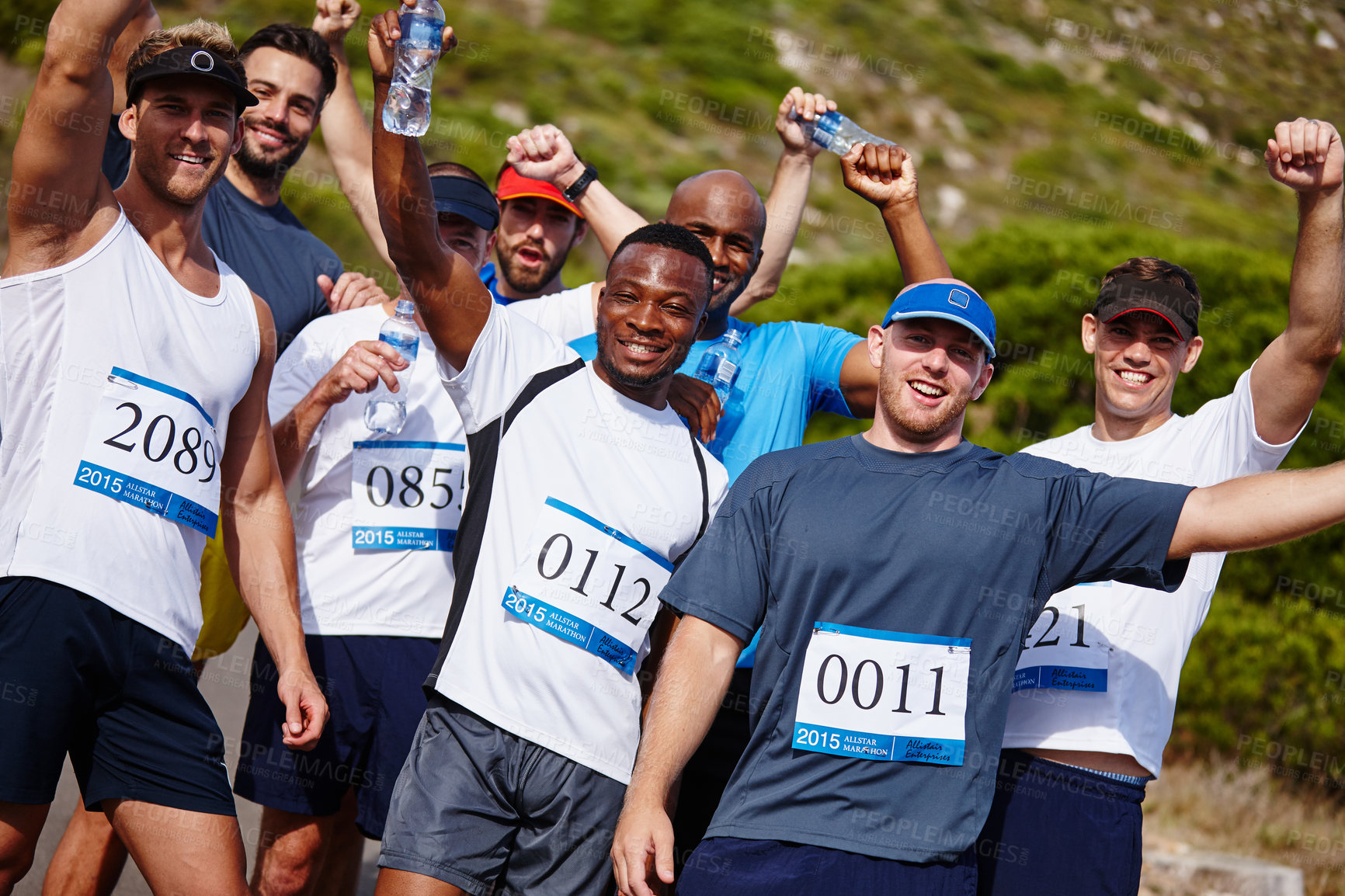 Buy stock photo A group of young men standing together with their water bottles after running a marathon