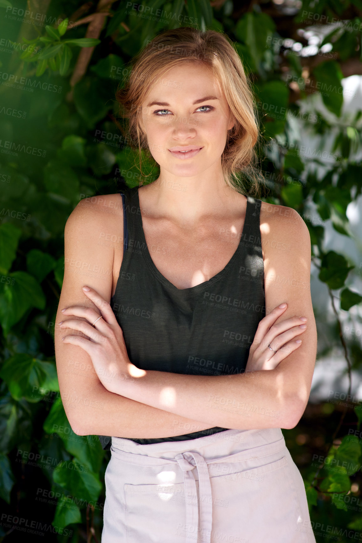 Buy stock photo A young woman wearing an apron standing with her arms 