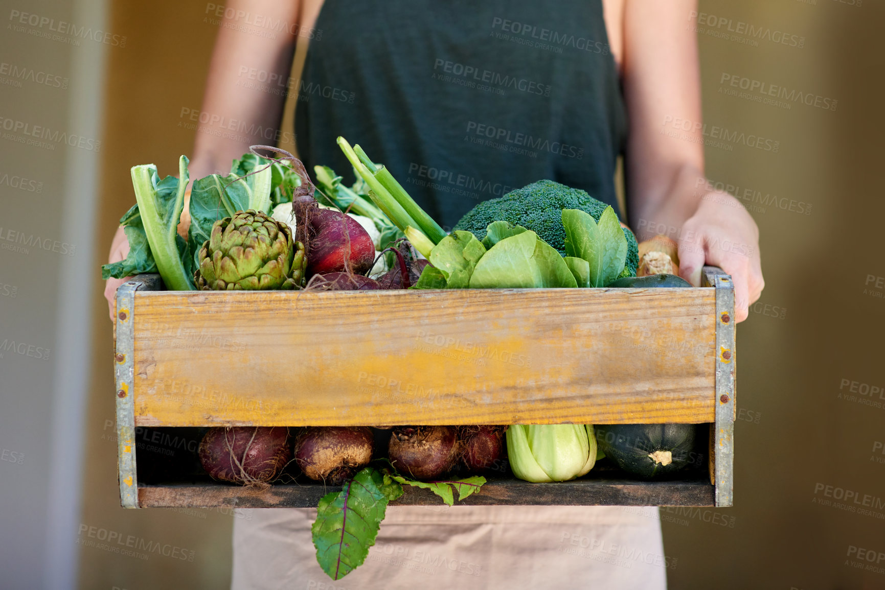 Buy stock photo A young woman holding a crate of vegetables outdoors