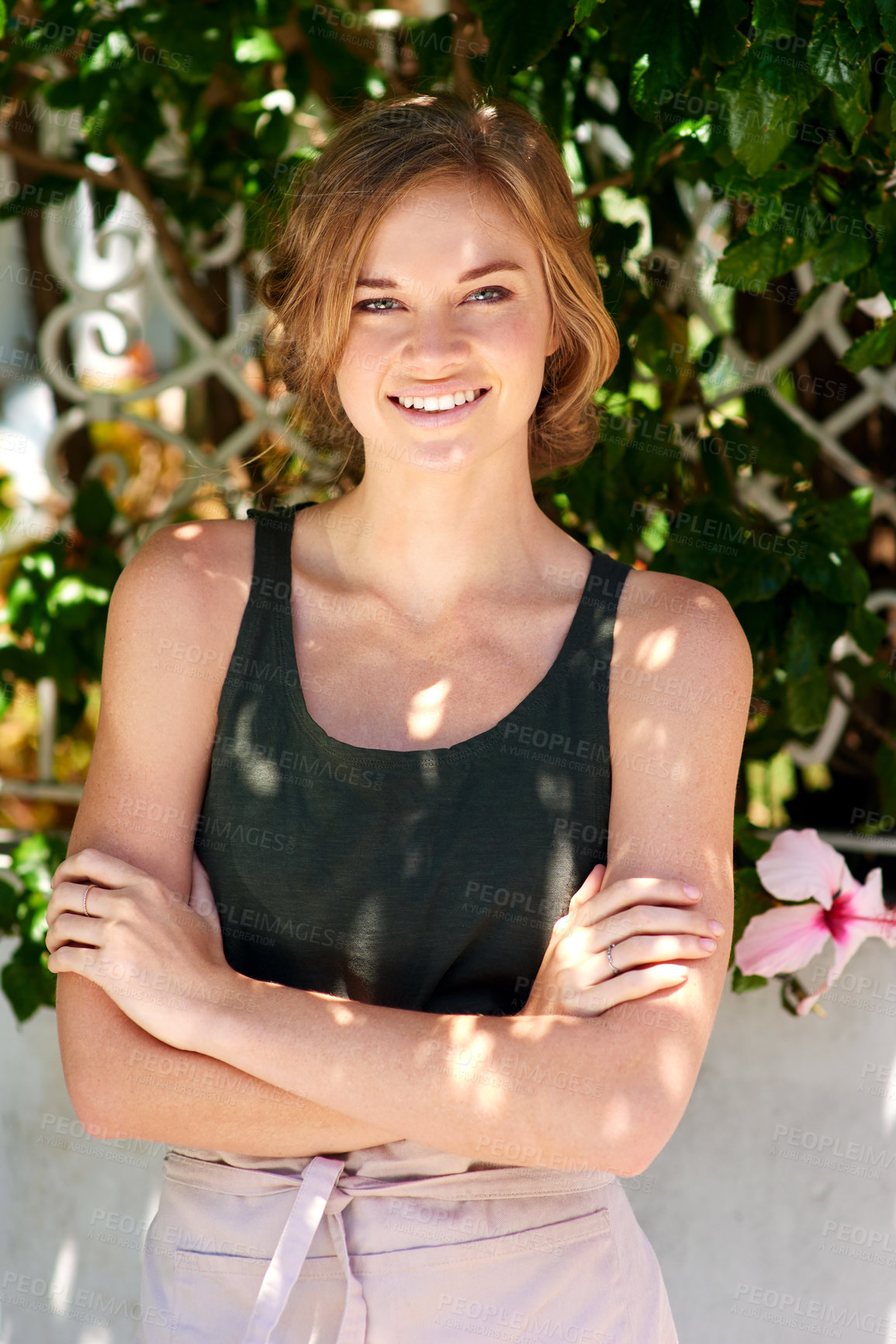 Buy stock photo A young woman wearing an apron standing with her arms 